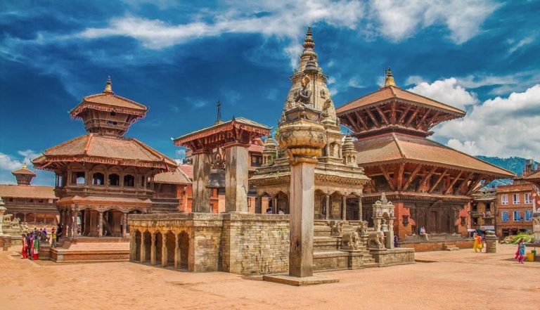 Wide scenic view of Nepal tourism featuring the Himalayan mountains, Mount Everest, colorful prayer flags, a traditional Buddhist stupa, and trekkers on a mountain trail near a valley landscape.